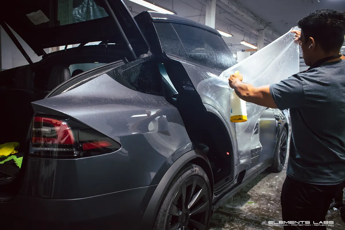 Elements Labs technician positioning paint protection film during a Tesla installation.