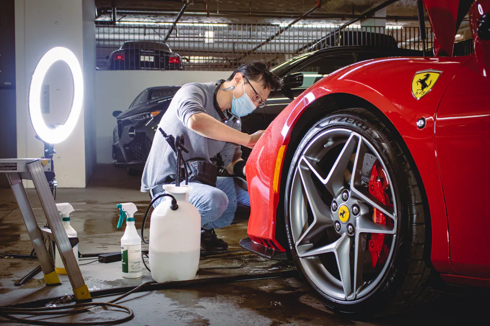 Elements Labs technician inspecting and preparing the front wheel arch of a red Ferrari.