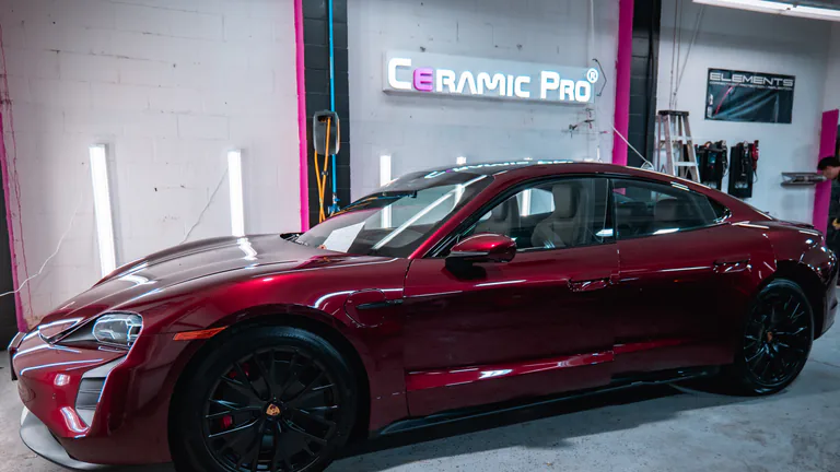 Red Porsche Taycan under inspection lighting inside the Elements Labs studio.