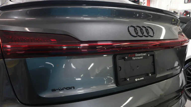 Black Audi rings and e-tron badging on a grey vehicle.